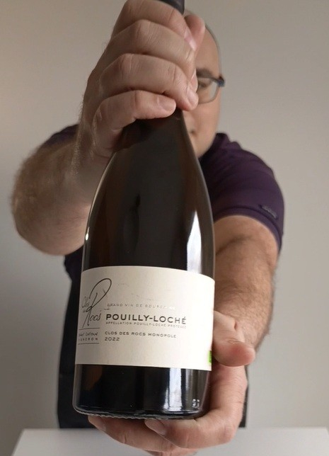 Sommelier holding a bottle of Clos des Rocs Pouilly-Loché 2022 Chardonnay from Burgundy.