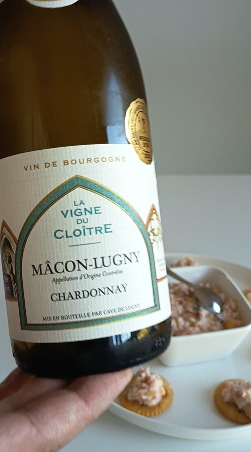 Close-up of a bottle of Cave de Lugny Mâcon-Lugny 'La Vigne du Cloître' French Chardonnay, with salmon rillettes appetizers on Ritz crackers in the background.