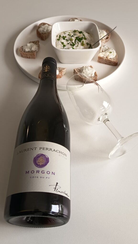 A bottle of Laurent Perrachon Morgon Côte du Py French red wine paired with traditional Lyonnais herbed cheese dip Cervelle des Canuts on crostini.