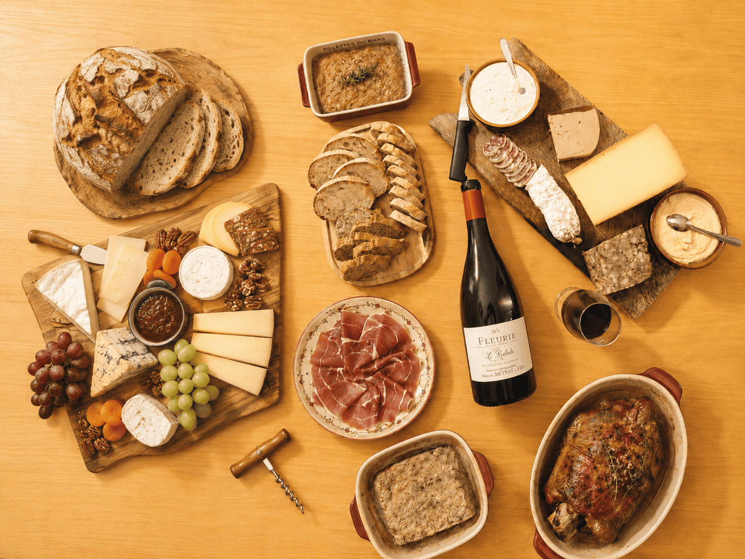 Top-down view of a bottle of Fleurie Beaujolais red wine served with an abundant French charcuterie and cheese board, rustic bread, and rillettes.