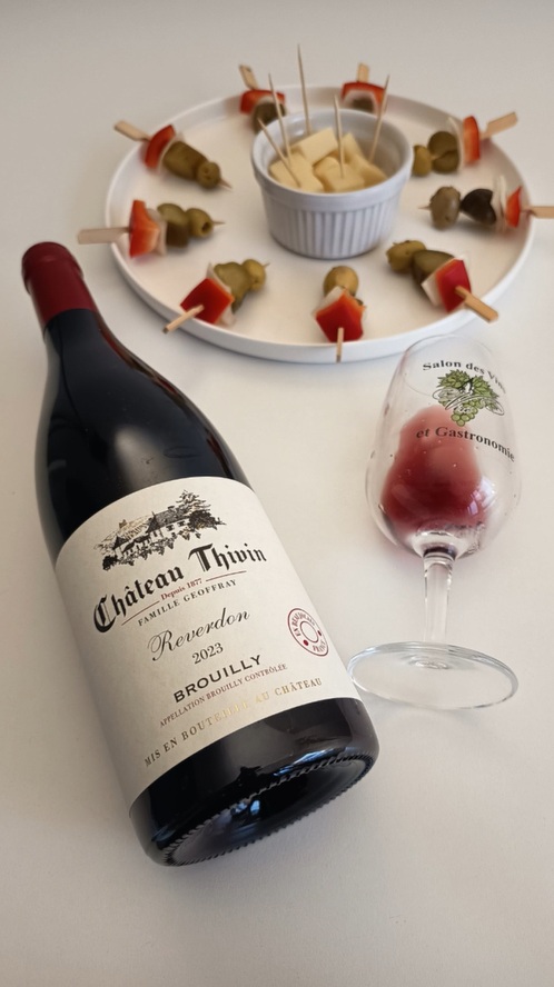Bottle of Château Thivin Brouilly Beaujolais red wine served with casual appetizer skewers and cheese for a relaxed French-style aperitif.