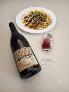 Bottle of Chénas Quartz 2020 by D. Piron next to a wine glass and plate of beef stroganoff with mushrooms and egg noodles